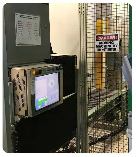 Laser marking control screen mounted on a stand next to a caged conveyor
