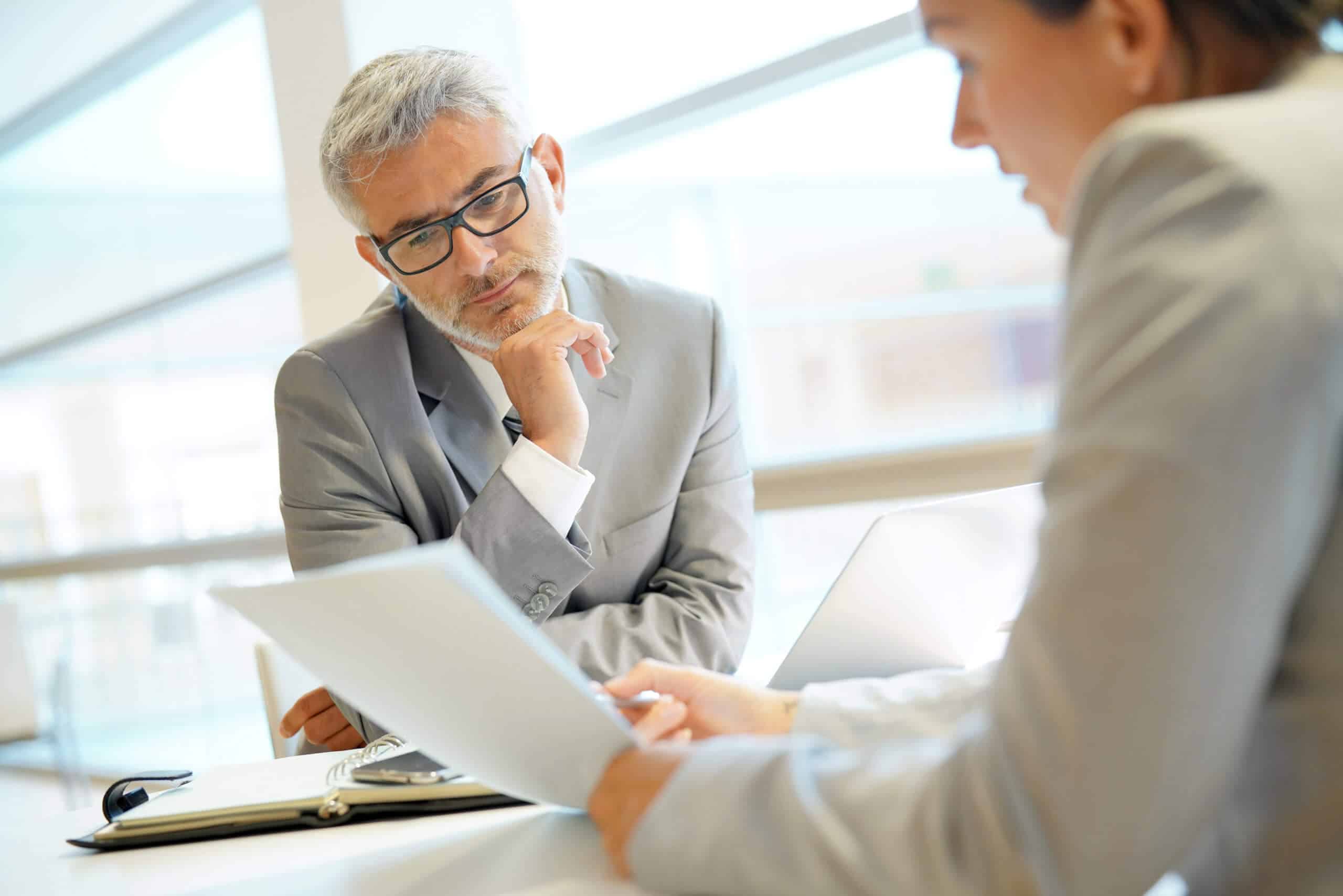 Businessman listening thoughtfully while a colleague explains a document