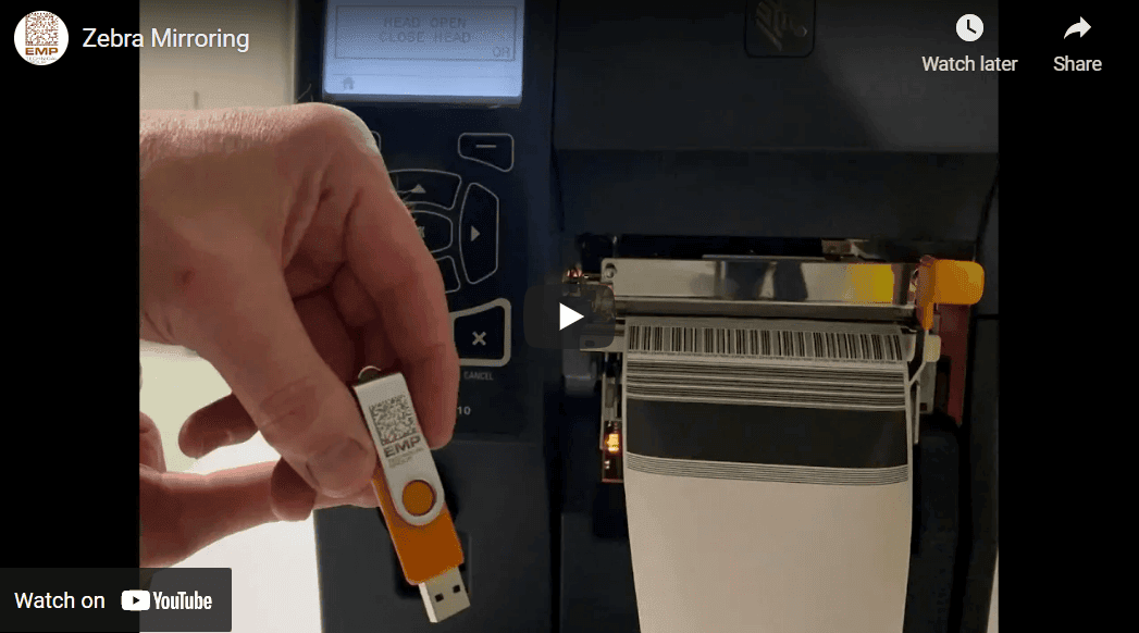 Screenshot of the Zebra Mirroring video: a hand holding a USB flash drive next to a Zebra industrial printer