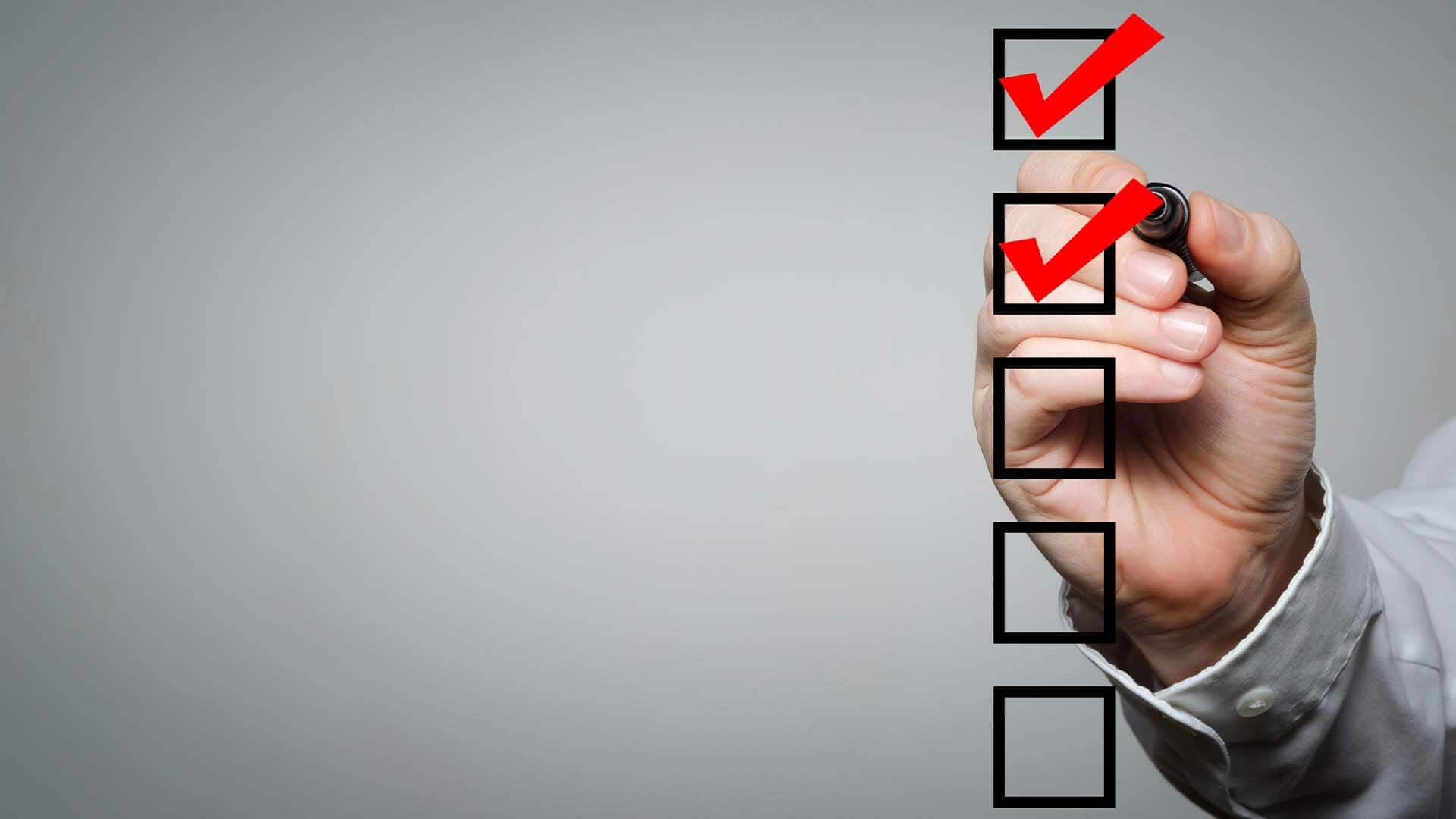 Hand ticking boxes on a checklist with a red marker