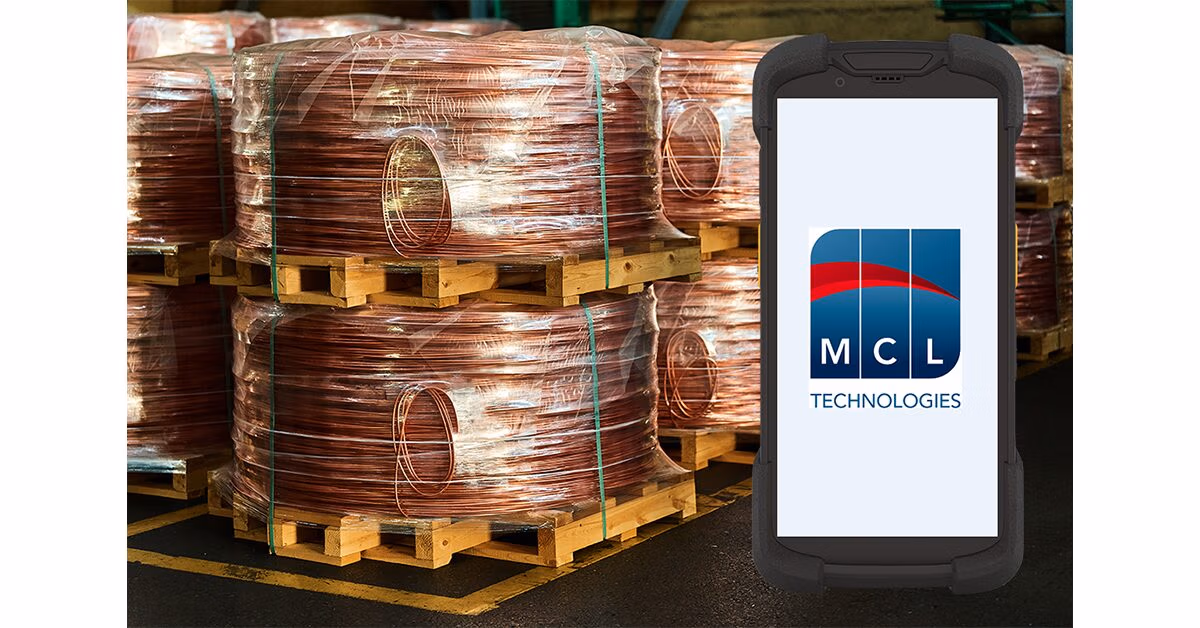 Handheld mobile computer running MCL Technologies software in front of pallets of copper wire coils