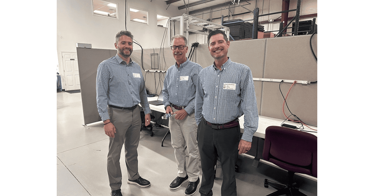 Three EMP team members in checked shirts standing in the office during the open house
