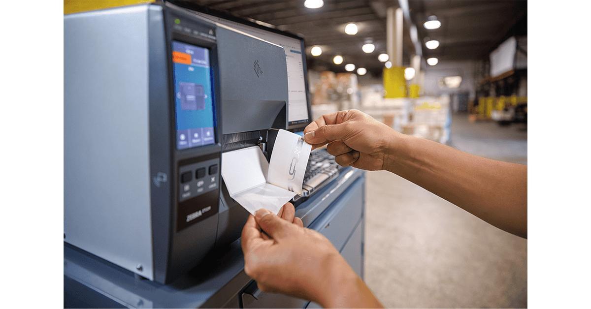 Worker removing a printed RFID label from a Zebra industrial printer in a warehouse