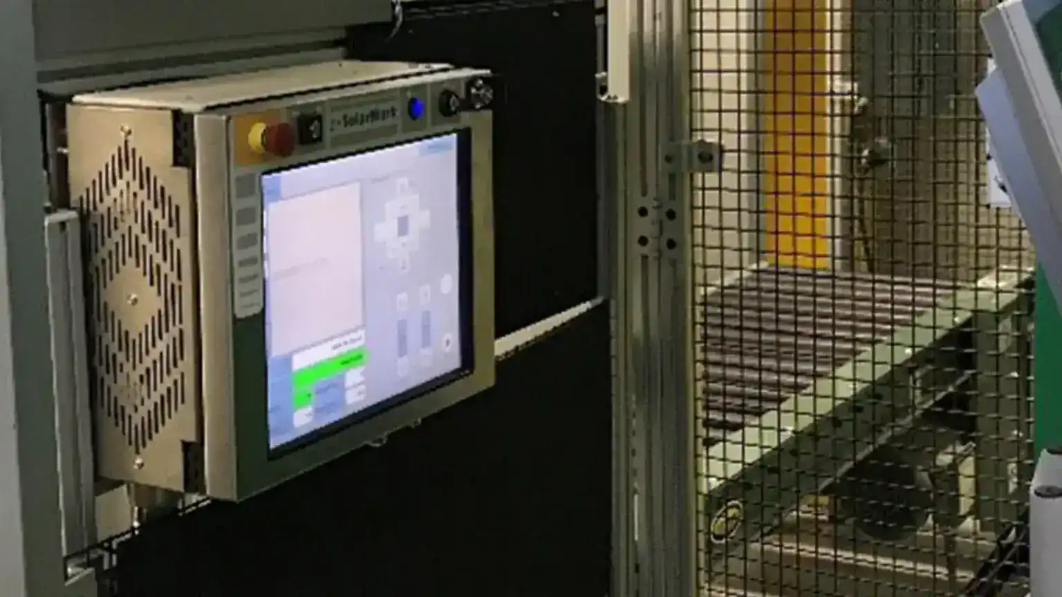 Laser marking control screen mounted on a stand next to a caged conveyor