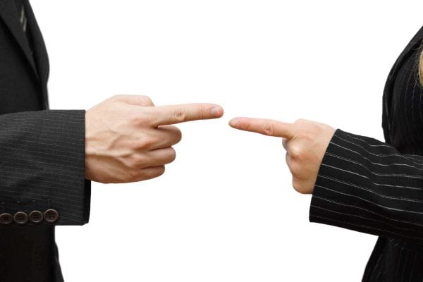 man and woman pointing at each other against. Business conflict Two people in business suits pointing fingers at each other