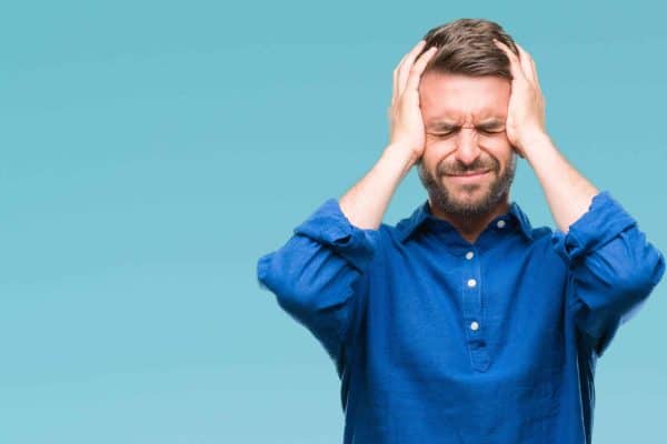 Frustrated man in a blue shirt holding his head with both hands