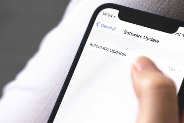 Hand holding a phone open to the Software Update screen with Automatic Updates turned on