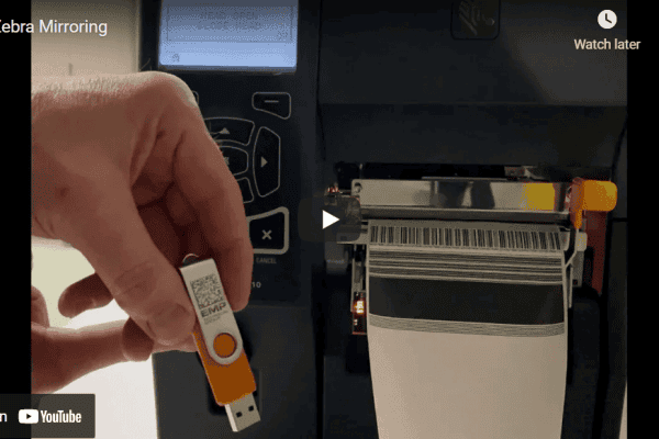 Screenshot of the Zebra Mirroring video: a hand holding a USB flash drive next to a Zebra industrial printer