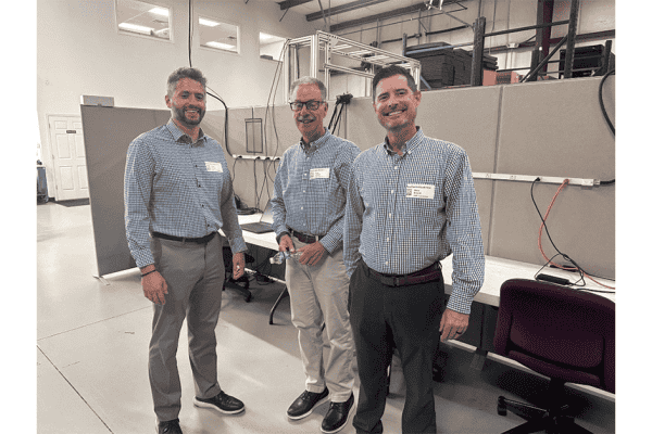 Three EMP team members in checked shirts standing in the office during the open house